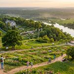 Квітуча долина річки з історичними будівлями під час золотого заходу сонця.