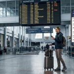 Traveler checks train departures on a smartphone at a station.